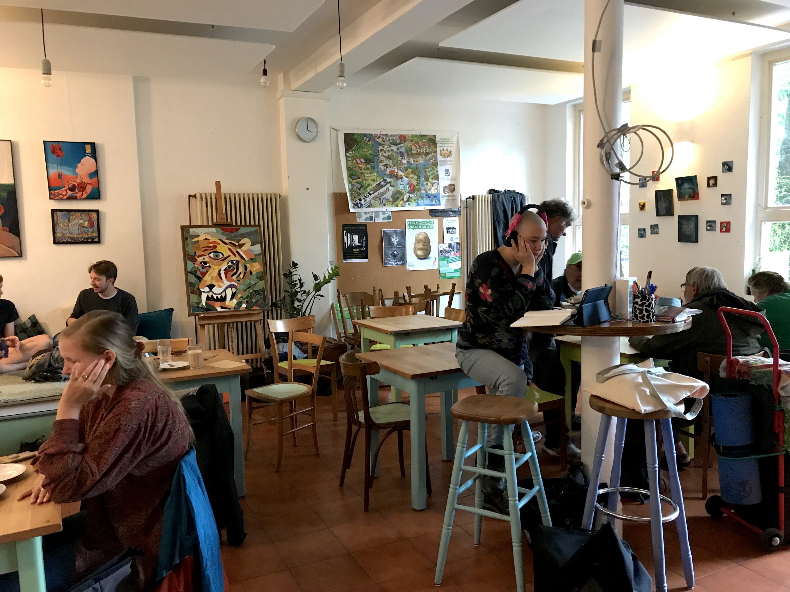 Bunte Tische, Hocker und Bilder im Raum vom Foodsharing Café